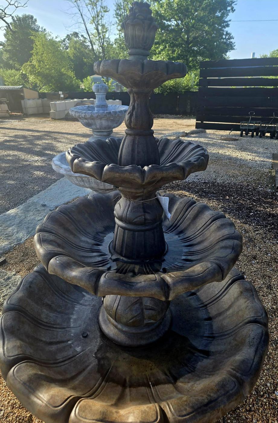 A three tier stone fountain on display in the yard