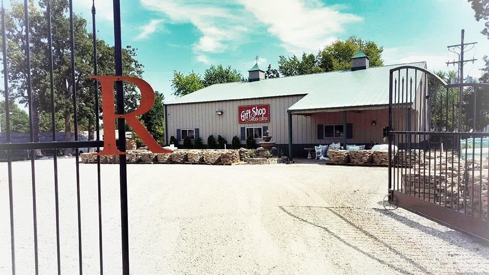 The entrance gates at Richart's Stone and Garden, with the big red R, pallets of stone along the building and the Gift Shop and Garden Center sign