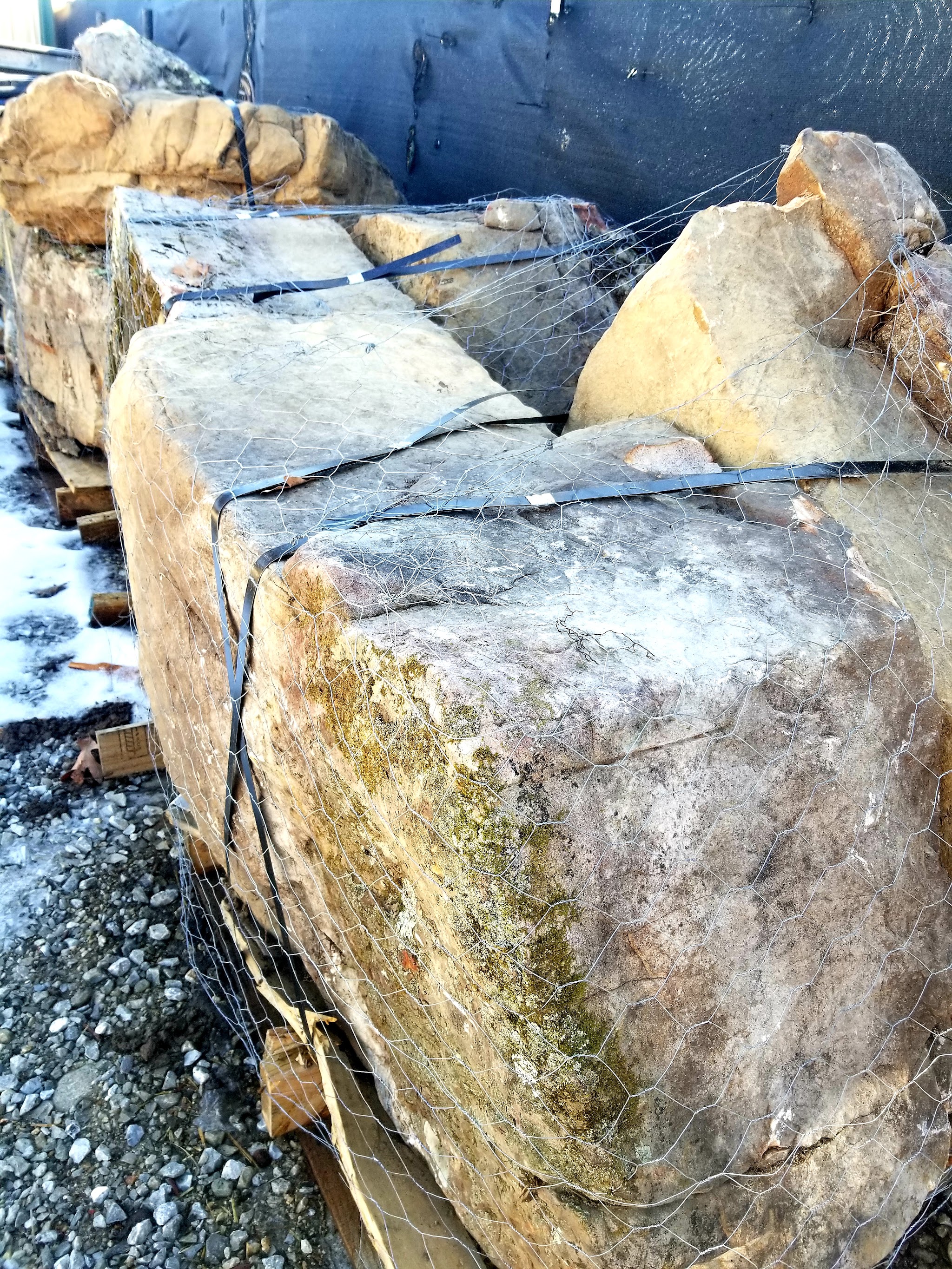 Large sandstone boulders strapped to pallets in the yard