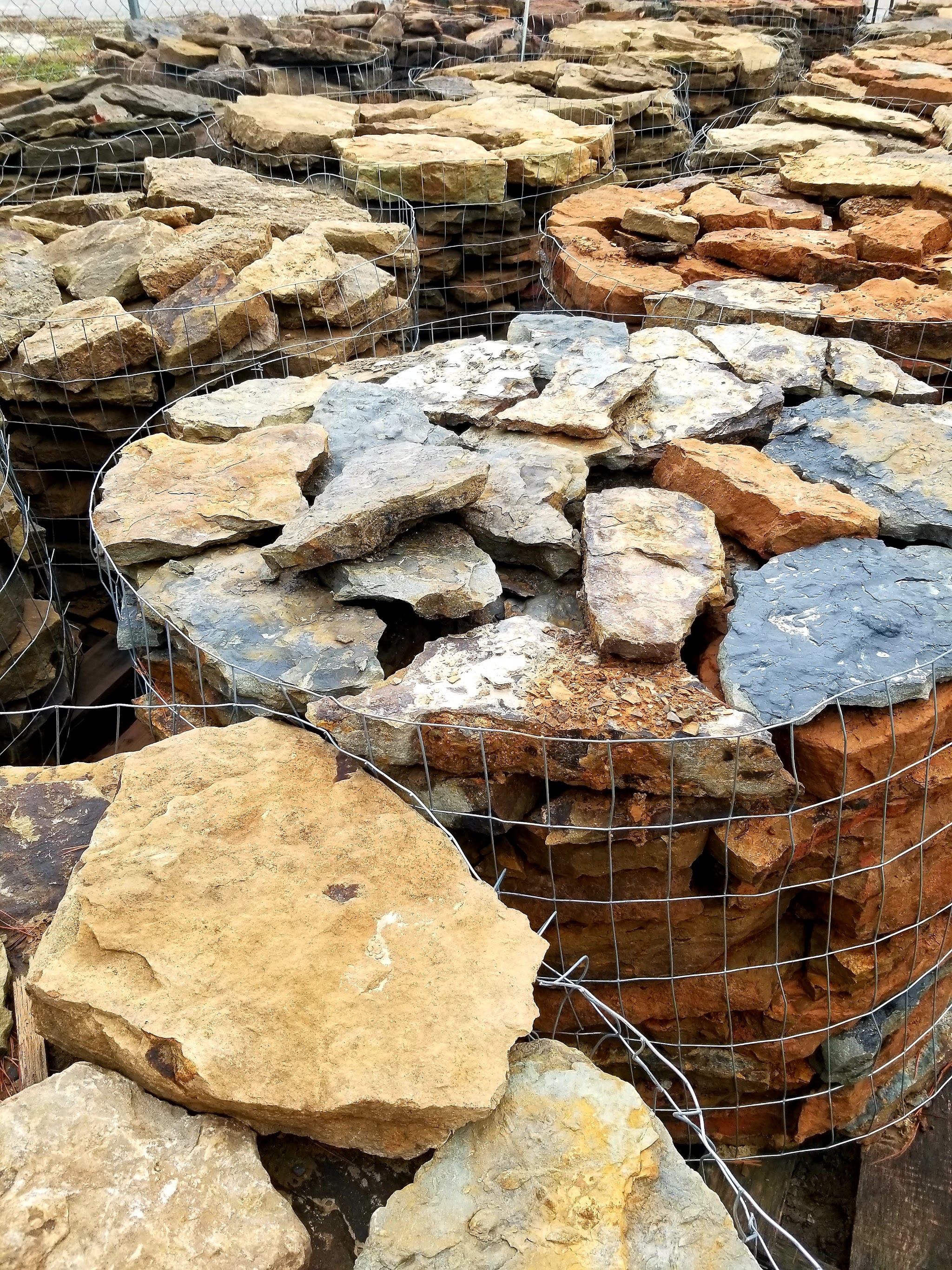Pallets of flagstone in gold, blue grey and rust at the stone yard